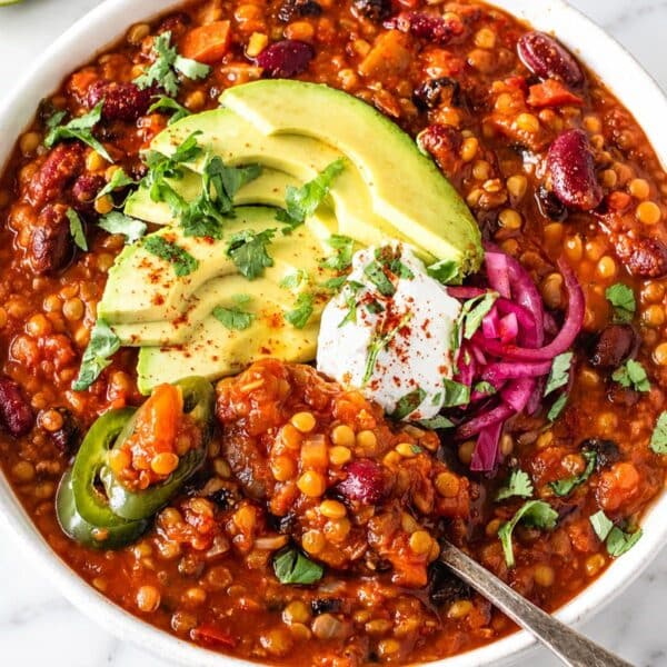 Lentil chili topped with cilantro, avocado, and Greek yogurt on Carrara marble.