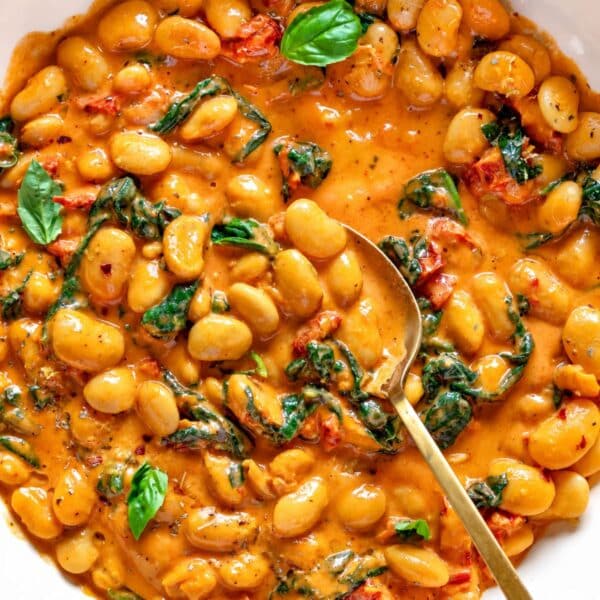 Marry me butter beans in a skillet with creamy sauce and fresh basil.