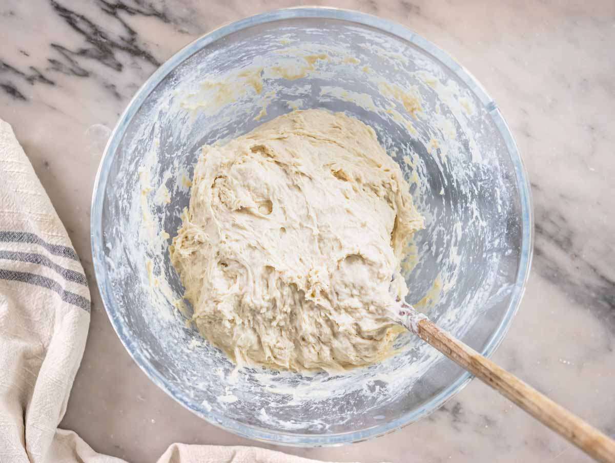 Step 2 Sticky focaccia dough mixed in bowl with wooden spoon.