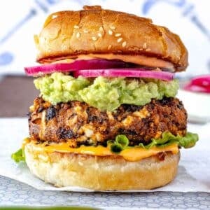 Black Bean Burger with buttered buns, chipotle sauce, guacamole, pickled onions, and lettuce.