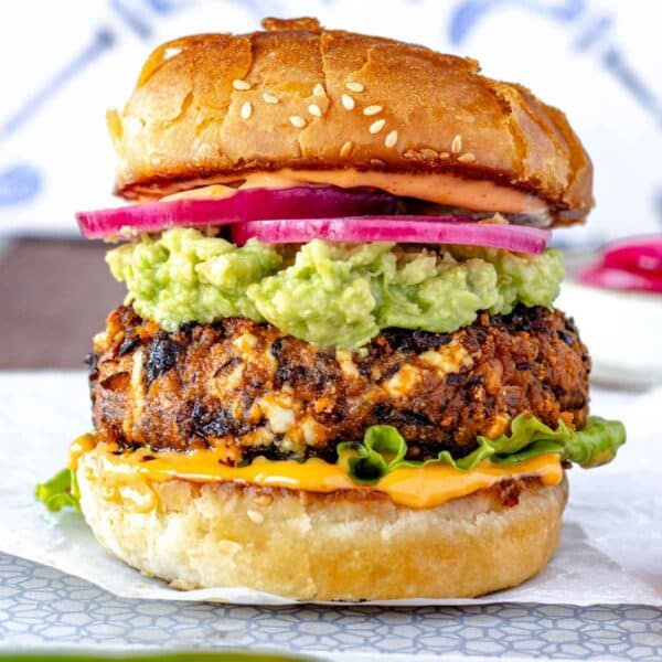 Black Bean Burger with buttered buns, chipotle sauce, guacamole, pickled onions, and lettuce.