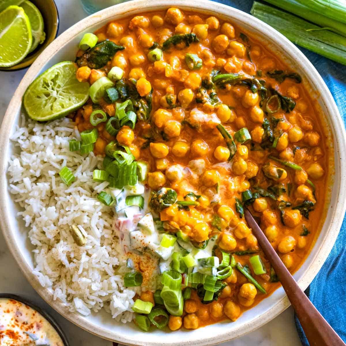 Creamy chickpea curry recipe with a spoon and rice.