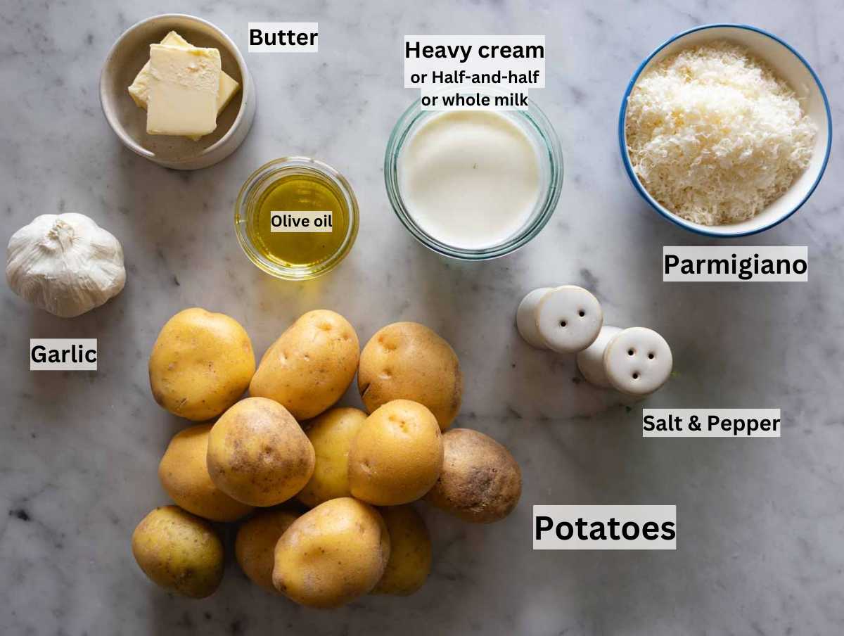 Ingredients for garlic mashed potatoes on a marble table.