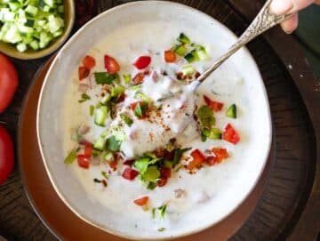 Raita with yogurt, cucumber, and tomatoes in a bowl