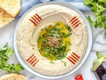 Baba ganoush on a plate topped with olive oil, parsley, and paprika.