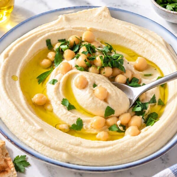 Homemade hummus with a creamy swirl, olive oil, chickpeas, and fresh parsley.