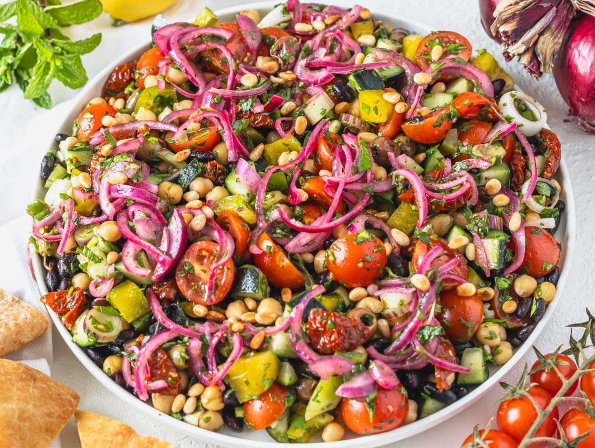 Mediterranean salad on a serving platter topped with pickled red onions.