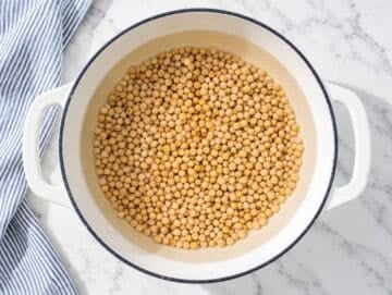 Step 1 Chickpeas simmering until very soft and tender in a pot on white marble.