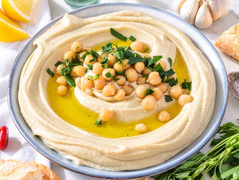 Step 3 Hummus spread into a blue bowl and garnished with olive oil, chickpeas, and parsley.
