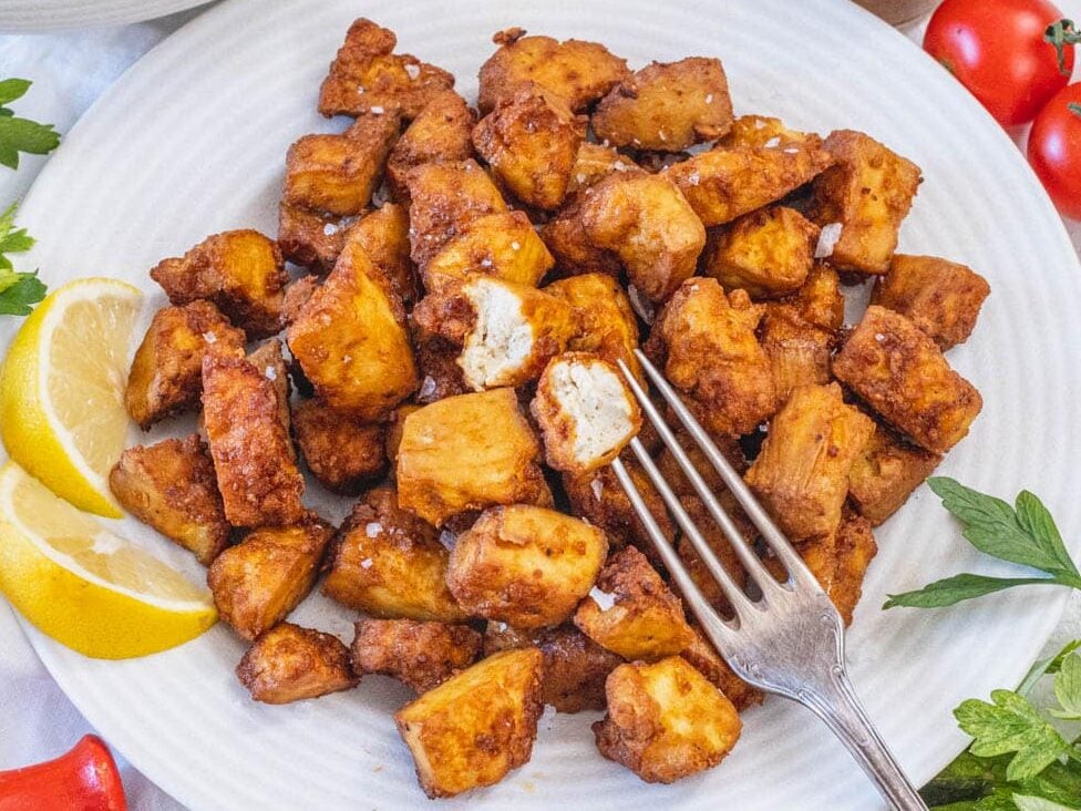 Air fryer tofu on a plate with lemon wedges