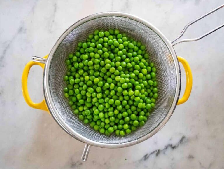 Blanched green peas in a sieve.