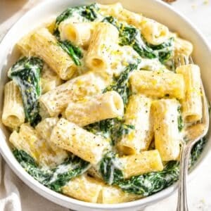 Bowl of lemon ricotta pasta on white Carrara marble in daylight.