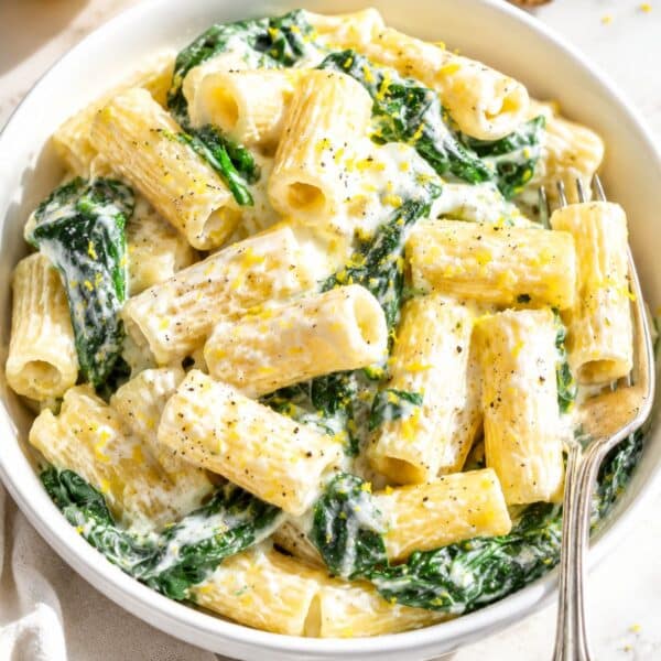 Bowl of lemon ricotta pasta on white Carrara marble in daylight.