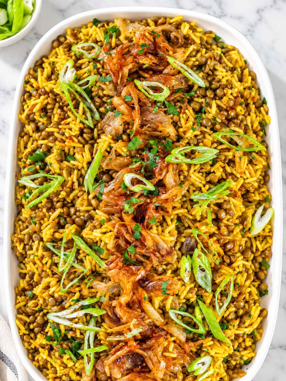 Close-up of mujadara showing tender lentils, rice, and glossy caramelized onions on a platter.
