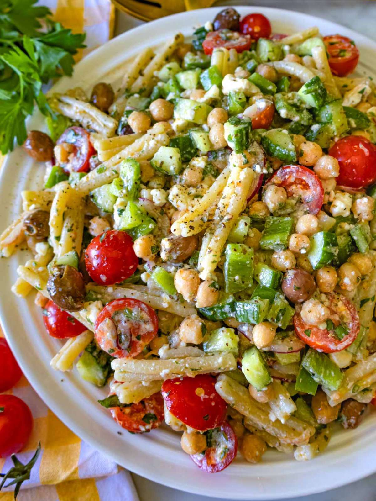 Close-up of pasta salad with red onion, cucumber, and crumbled feta – healthy Greek-style pasta salad with lemon olive oil dressing.