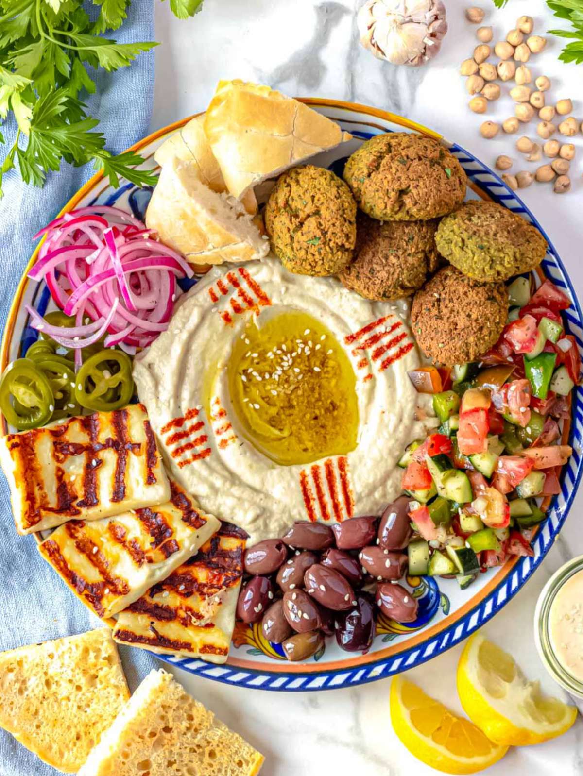 Meze platter with falafel, hummus, olives, halloumi, and pita bread.