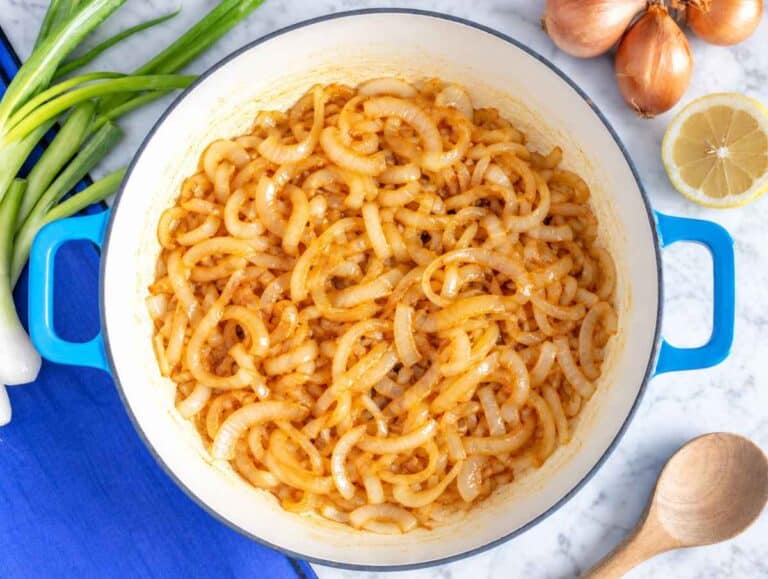 Step 1 Sliced onions cooking in a skillet until soft, golden, and deeply caramelized.
