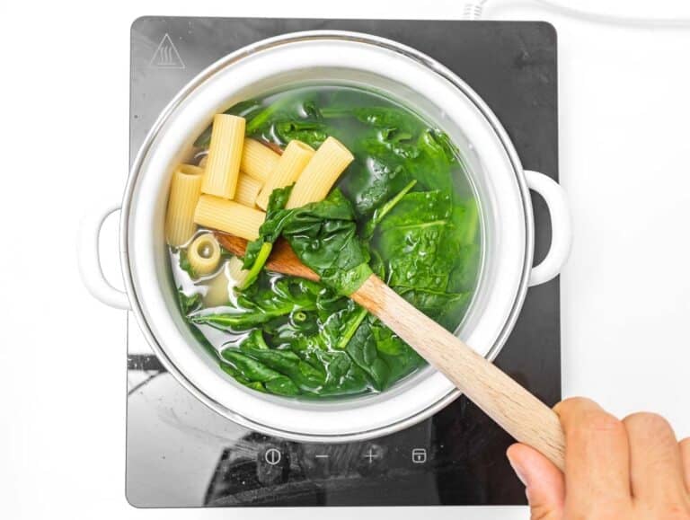rigatoni pasta cooking with spinach.