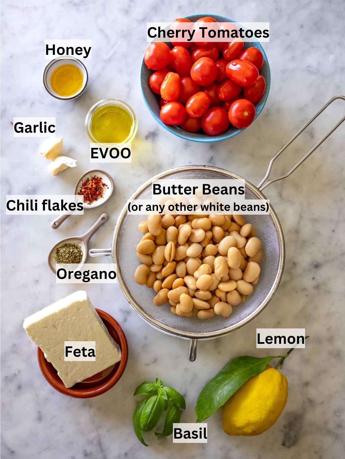 All ingredients for butter bean recipe, including butter beans, tomatoes, feta, lemon, and fresh herbs.