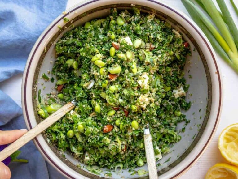 All ingredients for the kale quinoa salad tossed in the bowl with the dressing.