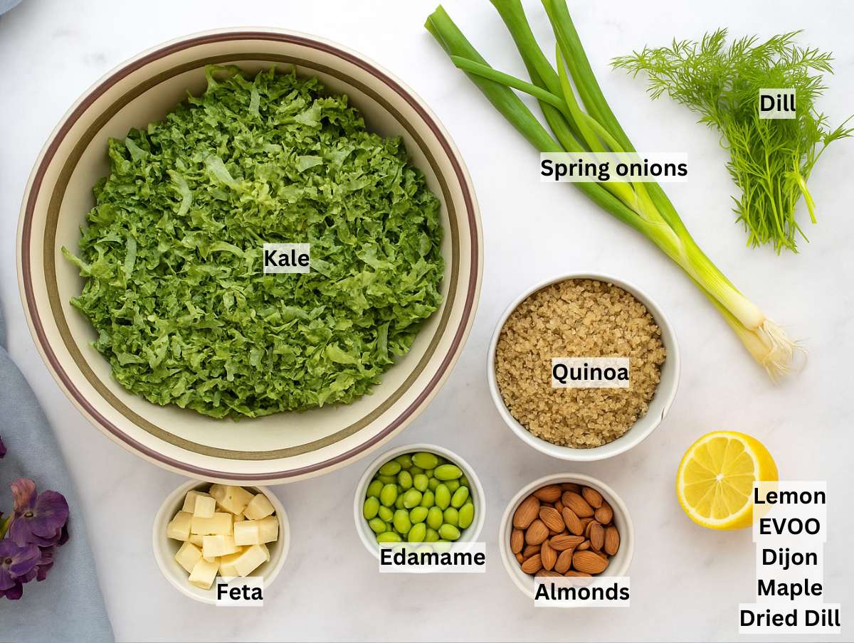 All ingredients for the kale quinoa salad tossed in the bowl with the dressingngredients for kale quinoa salad arranged on a marble surface, including chopped kale, cooked quinoa, edamame, feta, a