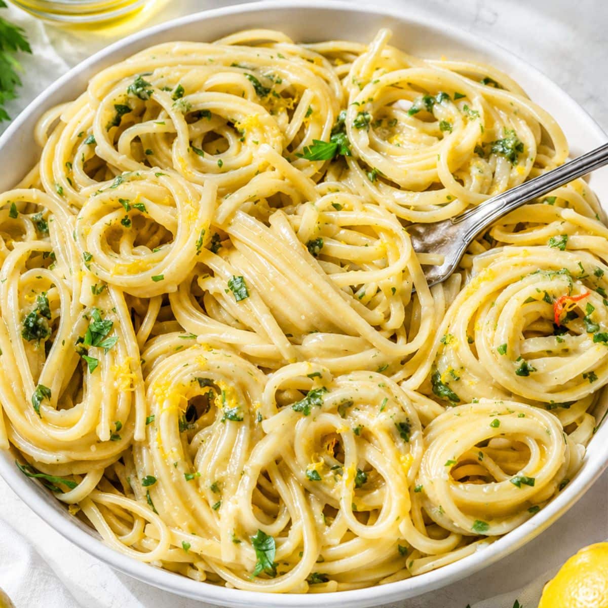 Bowl of Lemon Pasta on white marble with silver fork.