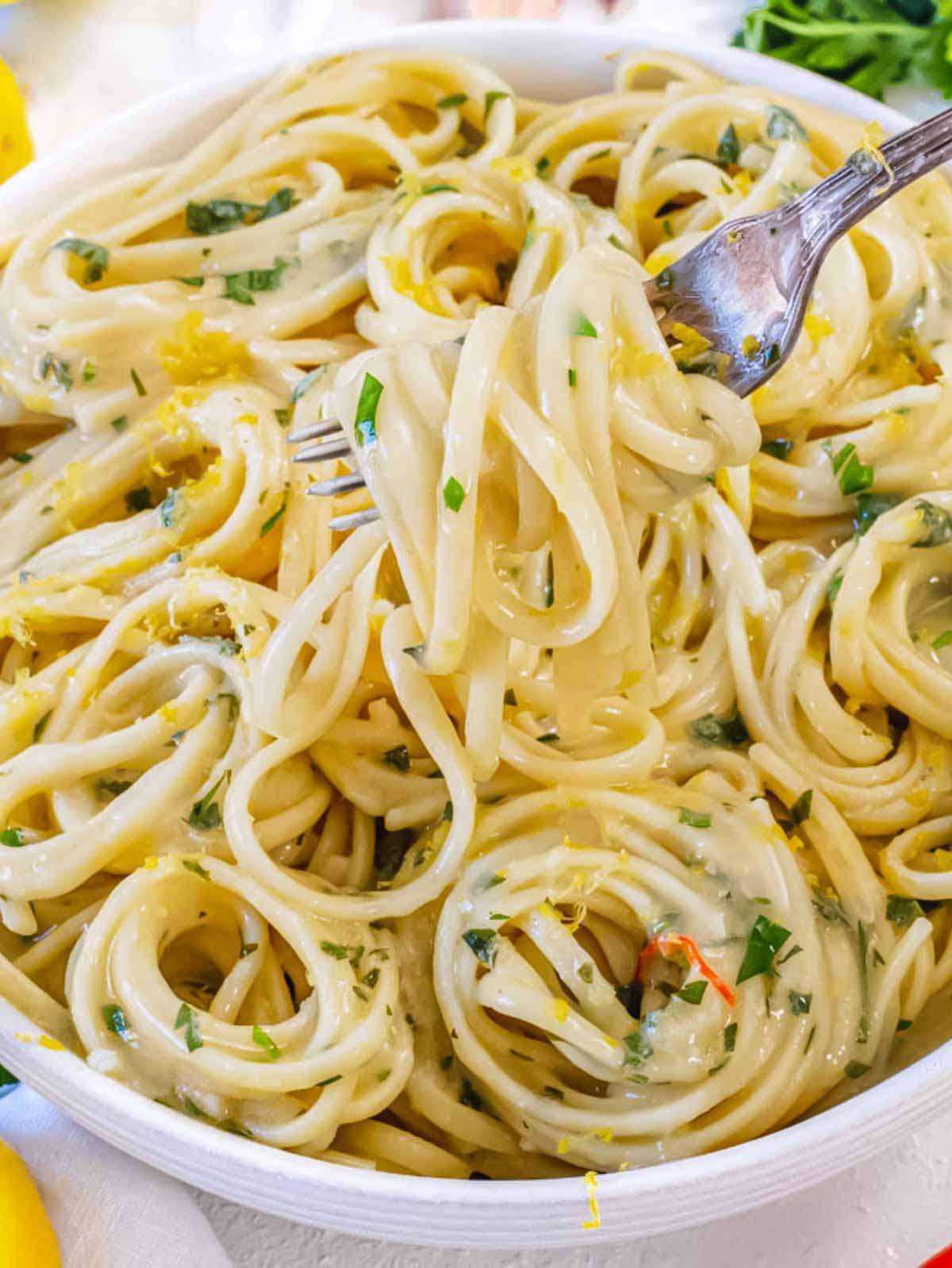 Close-up of a forkful of lemon pasta without cream, showing the creamy texture of the lemon garlic sauce clinging to the noodles.