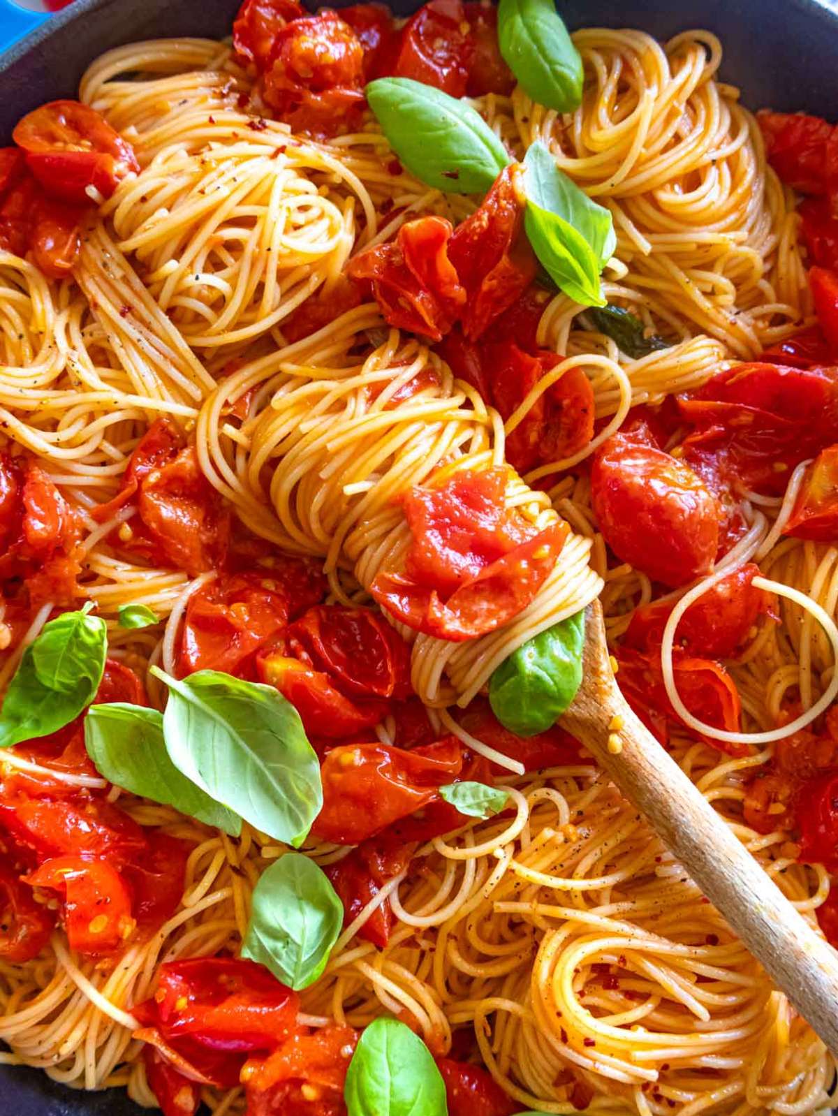 Close-up of angel hair pasta with juicy tomatoes, garlic, and melted parmesan cheese.
