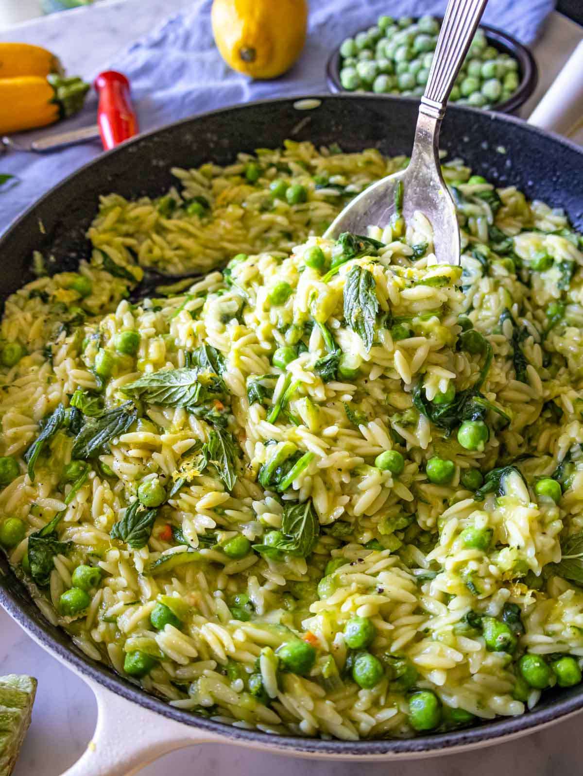 Close-up of creamy lemon orzo with zucchini and herbs, topped with parmesan and fresh mint.