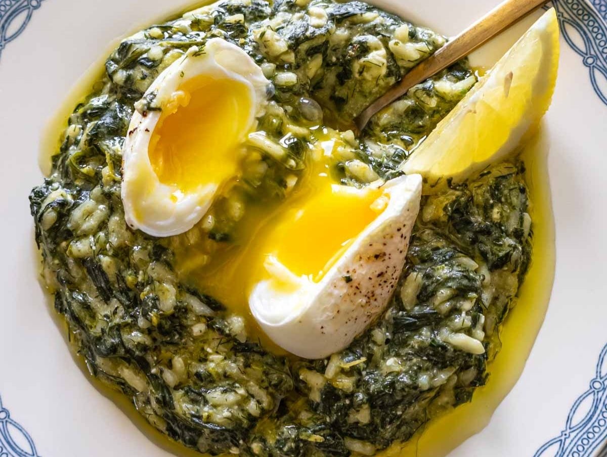 Close-up of spanakorizo Greek spinach and rice creamy texture with dill lemon and poached egg on top.