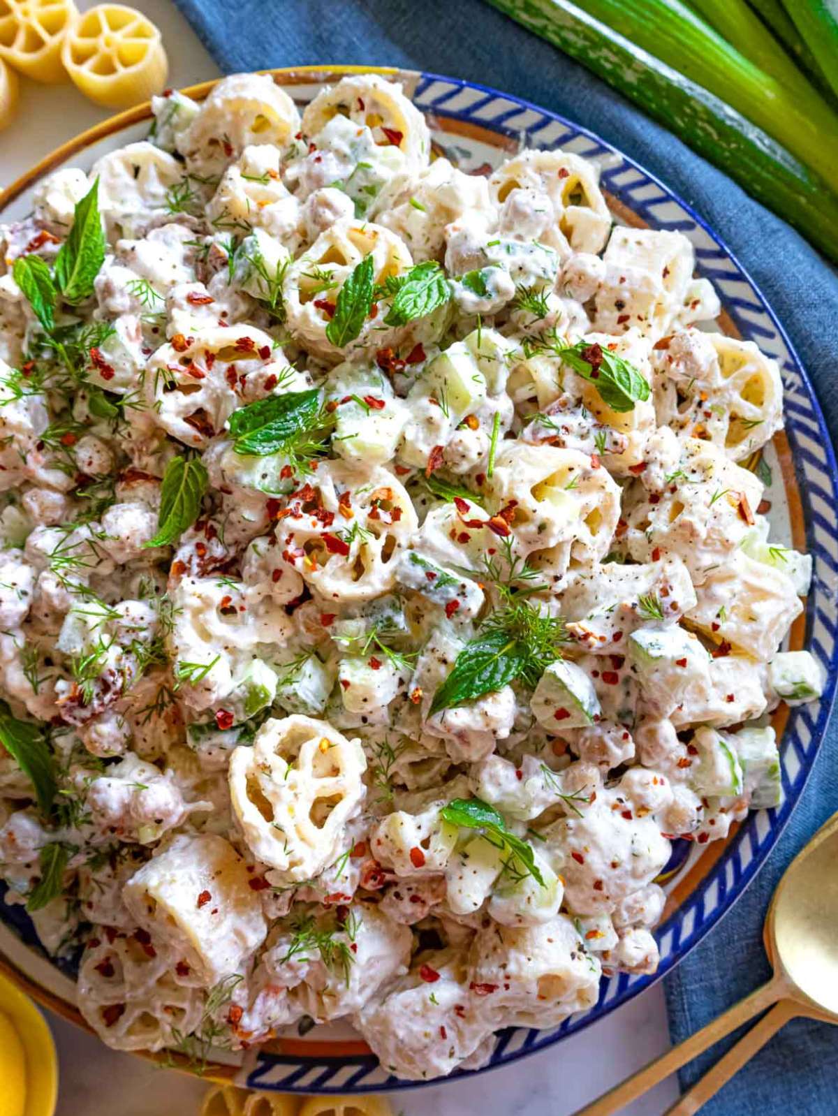 Cold pasta salad with chickpeas and creamy dressing, served in a large blue platter.