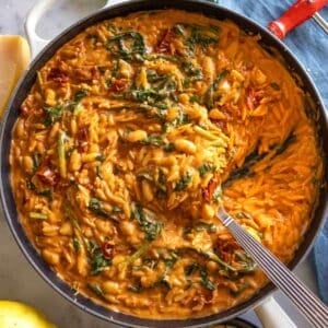 Creamy Marry Me Orzo in skillet with spoon, ready to serve, cozy dinner vibes.
