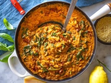 Creamy marry me orzo in a skillet with a spoon.