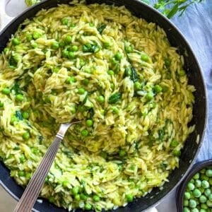 Creamy orzo with lemon and peas in a skillet.