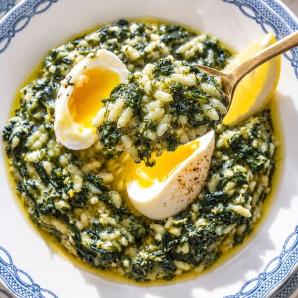 Creamy spanakorizo with spinach, eggs, dill, and lemon in natural light.