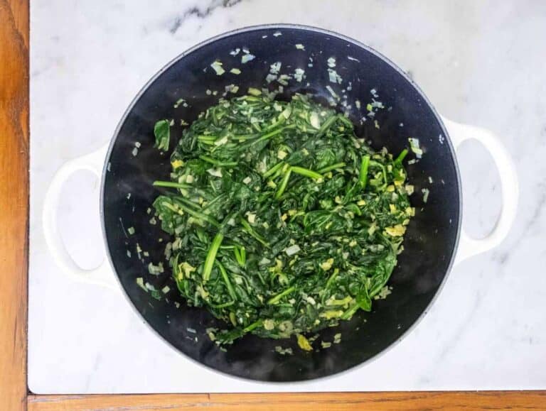 Fresh spinach wilting in pot with olive oil and salt for heart-healthy Greek one-pot meal.