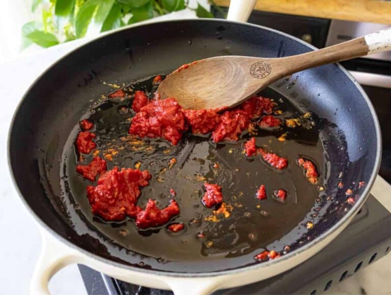 Garlic, chili, tomato paste sizzling in olive oil in skillet, beginning the Marry Me Orzo recipe.