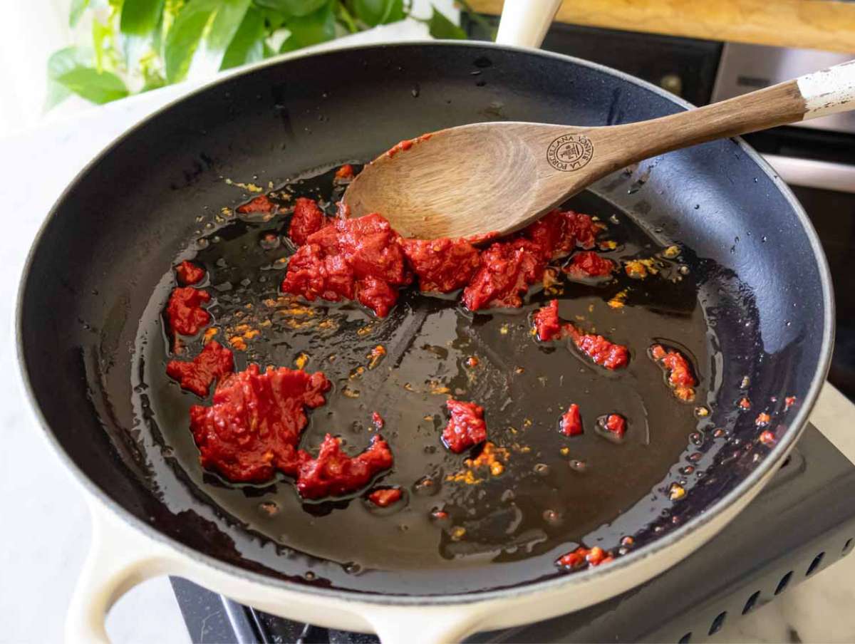 Garlic, chili, tomato paste sizzling in olive oil in skillet, beginning the Marry Me Orzo recipe.
