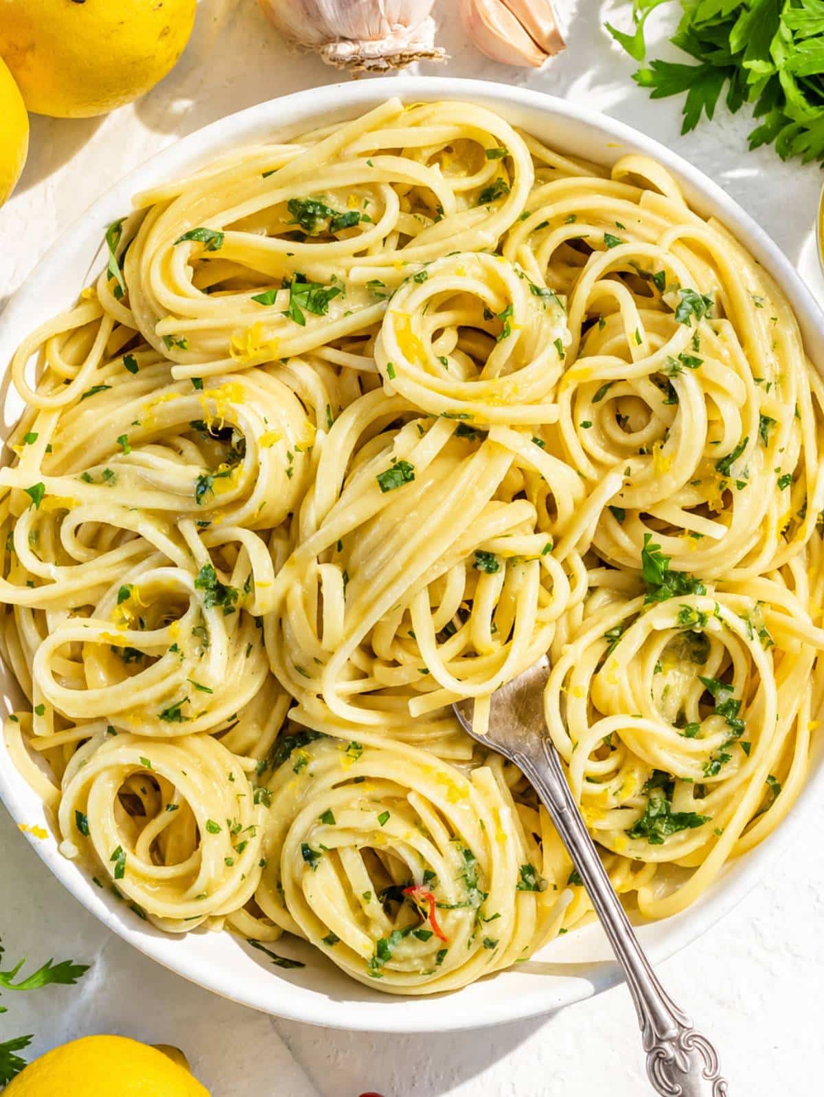 Glossy Lemon Pasta with parsley, parmesan, and lemon zest with a fork.