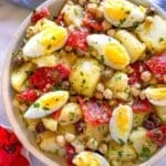 Healthy no-mayo potato salad in a rustic bowl with ingredients like chickpeas, celery, and roasted peppers in view.
