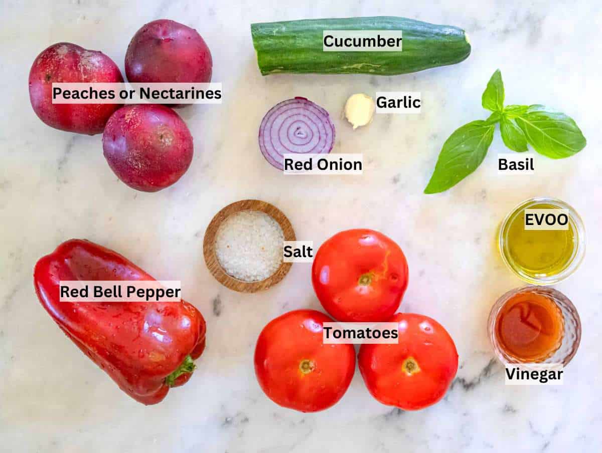 Ingredients for peach gazpacho arranged on a wooden board, ready to blend.
