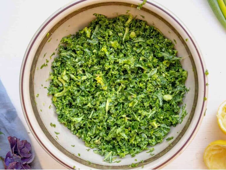 Massaged chopped kale with lemon and salt in a large bowl, softening the leaves for a nutritious anti-inflammatory salad