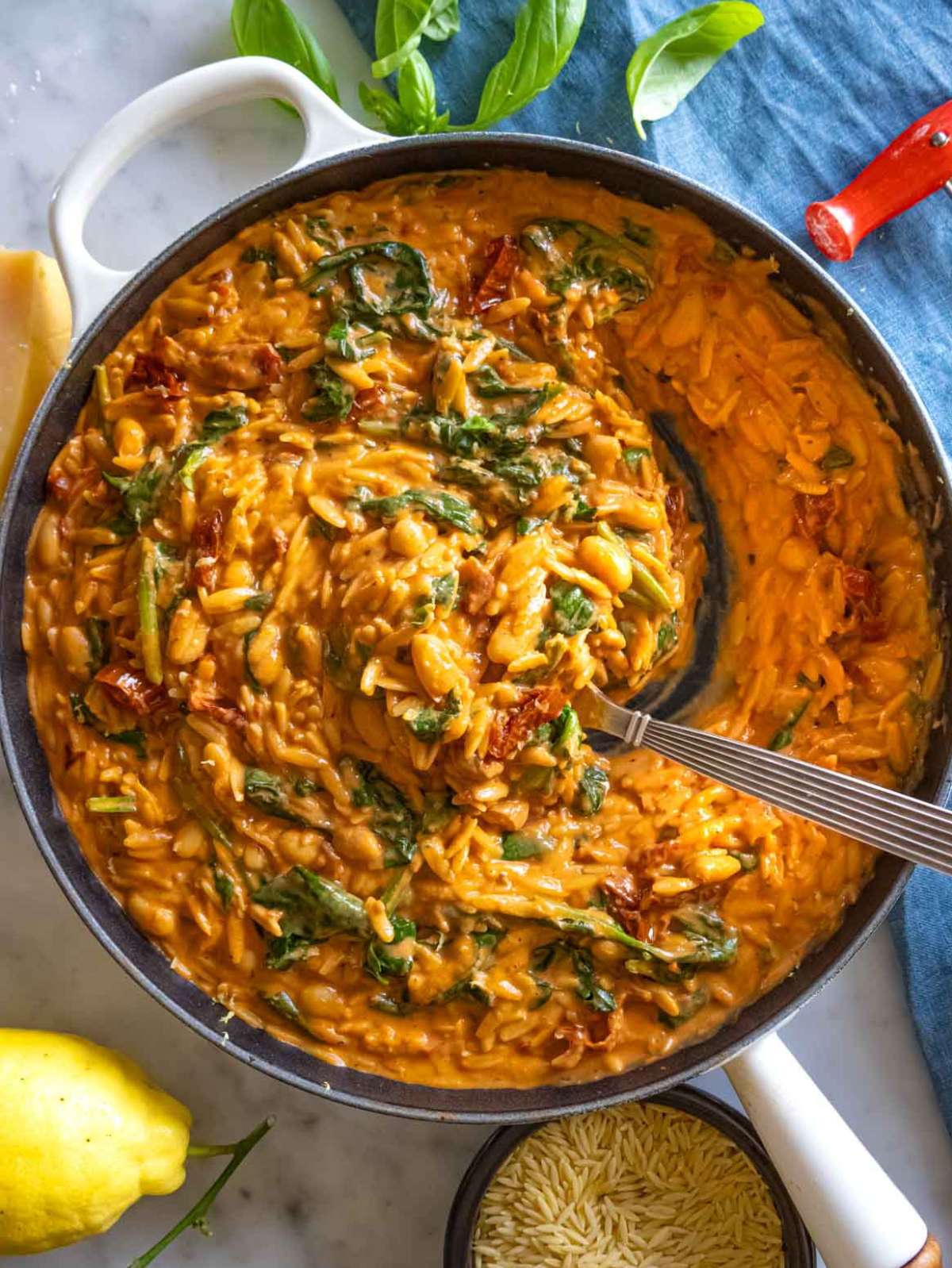 Merry me orzo in a skillet served with a squeeze of lemon.
