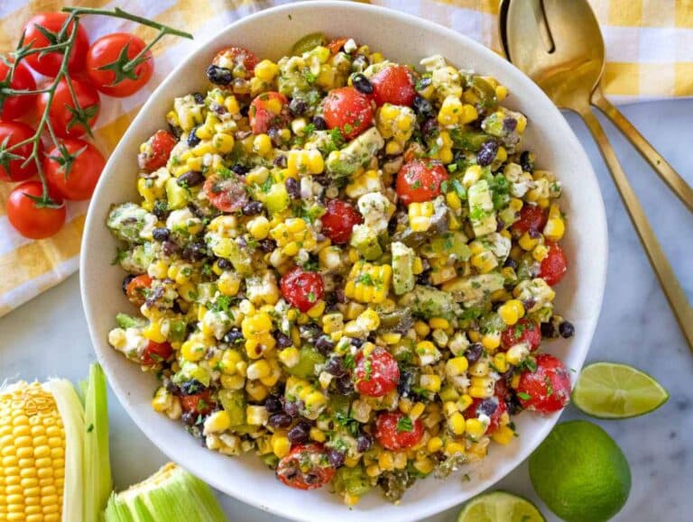 Mexican corn salad served in a hand made bowl with lime wedges.