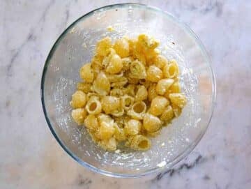 Mixing warm cooked pasta into the creamy feta dressing.
