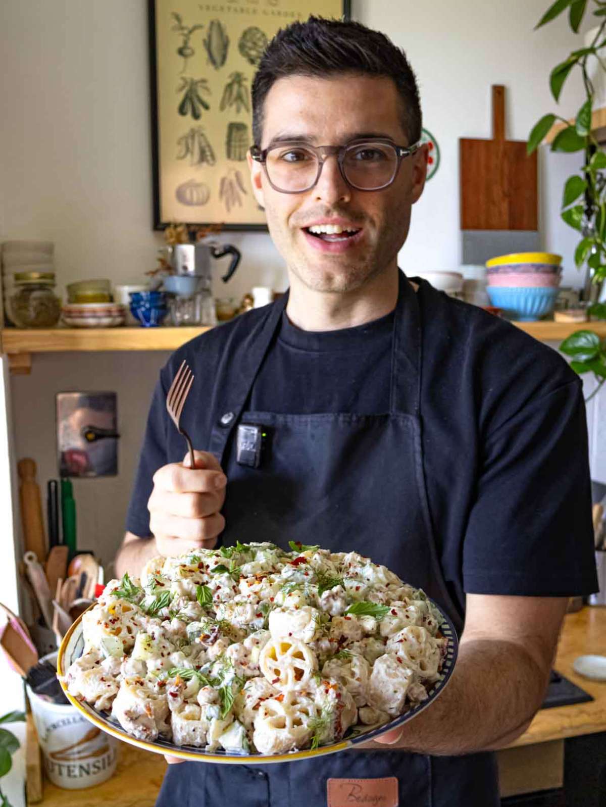 Nico holding a bowl of healthy cold pasta salad with a smile, ready to serve.