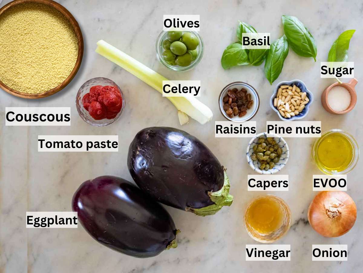 Raw ingredients for Mediterranean couscous salad, including eggplant, couscous, olives, tomato paste, celery, onion, and capers on a countertop.