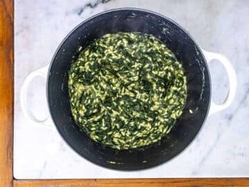 Risotto rice and broth added to sautéed vegetables cooking spanakorizo in one pot.