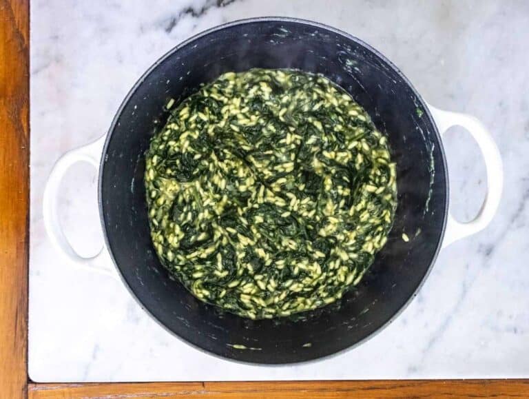 Risotto rice and broth added to sautéed vegetables cooking spanakorizo in one pot.