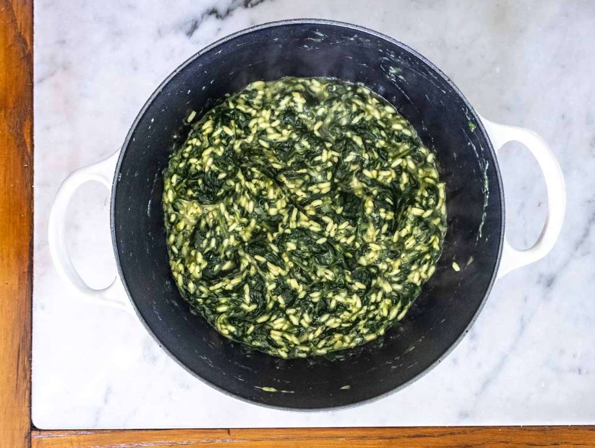 Risotto rice and broth added to sautéed vegetables cooking spanakorizo in one pot.